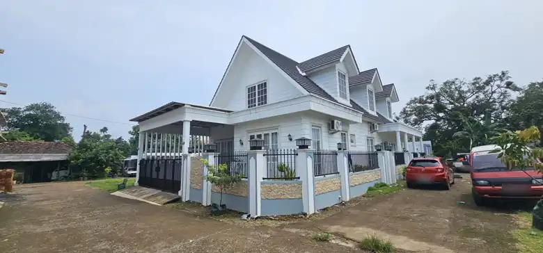 Rumah bergaya Cape Cod dengan pagar dan gerbang besi hitam, tampak sudut
